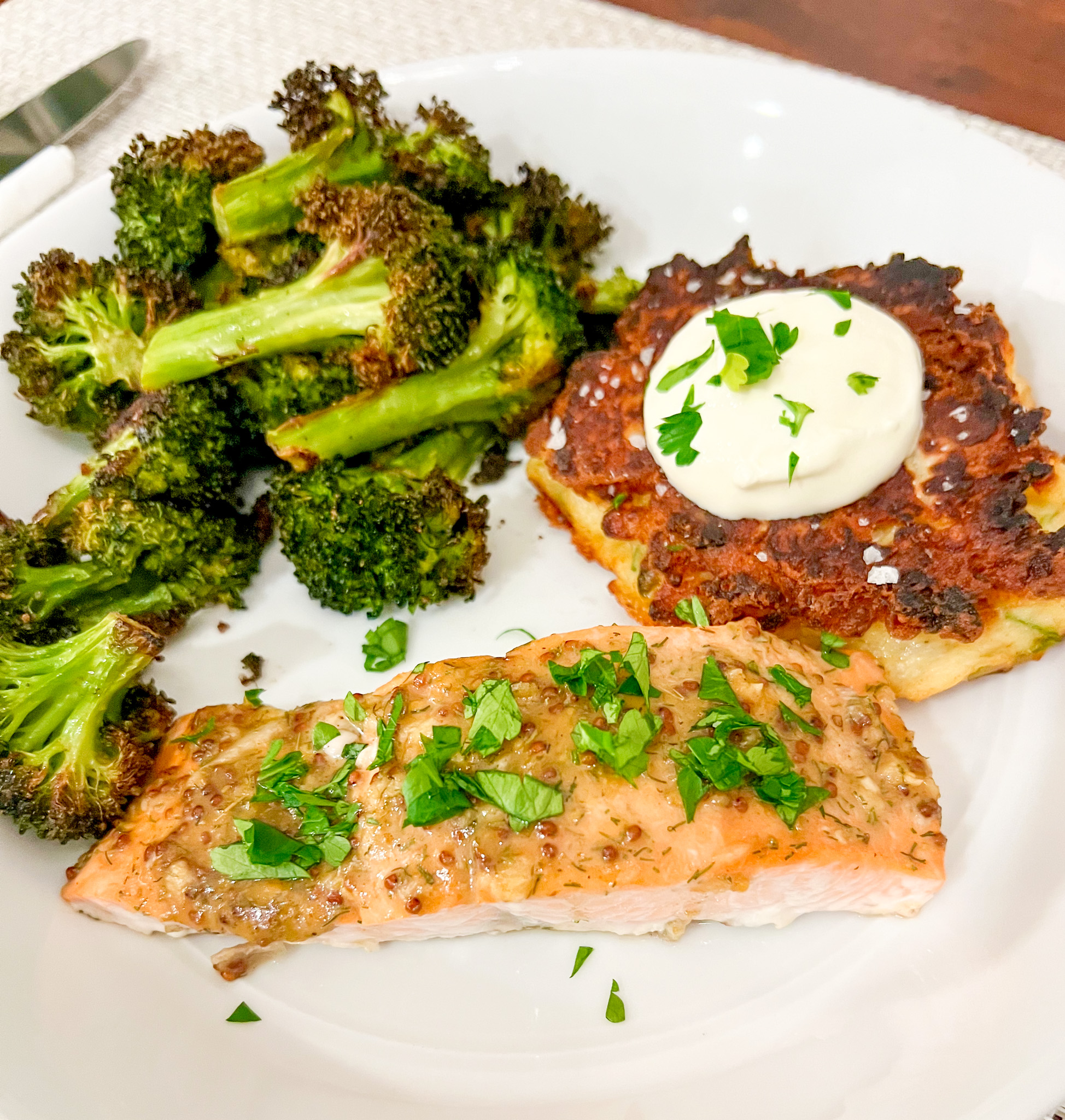 Baked honey mustard salmon on a white plate with roasted broccoli and a mashed potato cake.