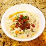 Chicken bacon sweet corn chowder ina white bowl on a counter top.