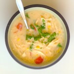 chicken, sweet corn and tomato soup in a bowl with a spoon and parsley on top