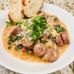 White bean and sausage skillet dish in a white bowl with two pieces of bread.