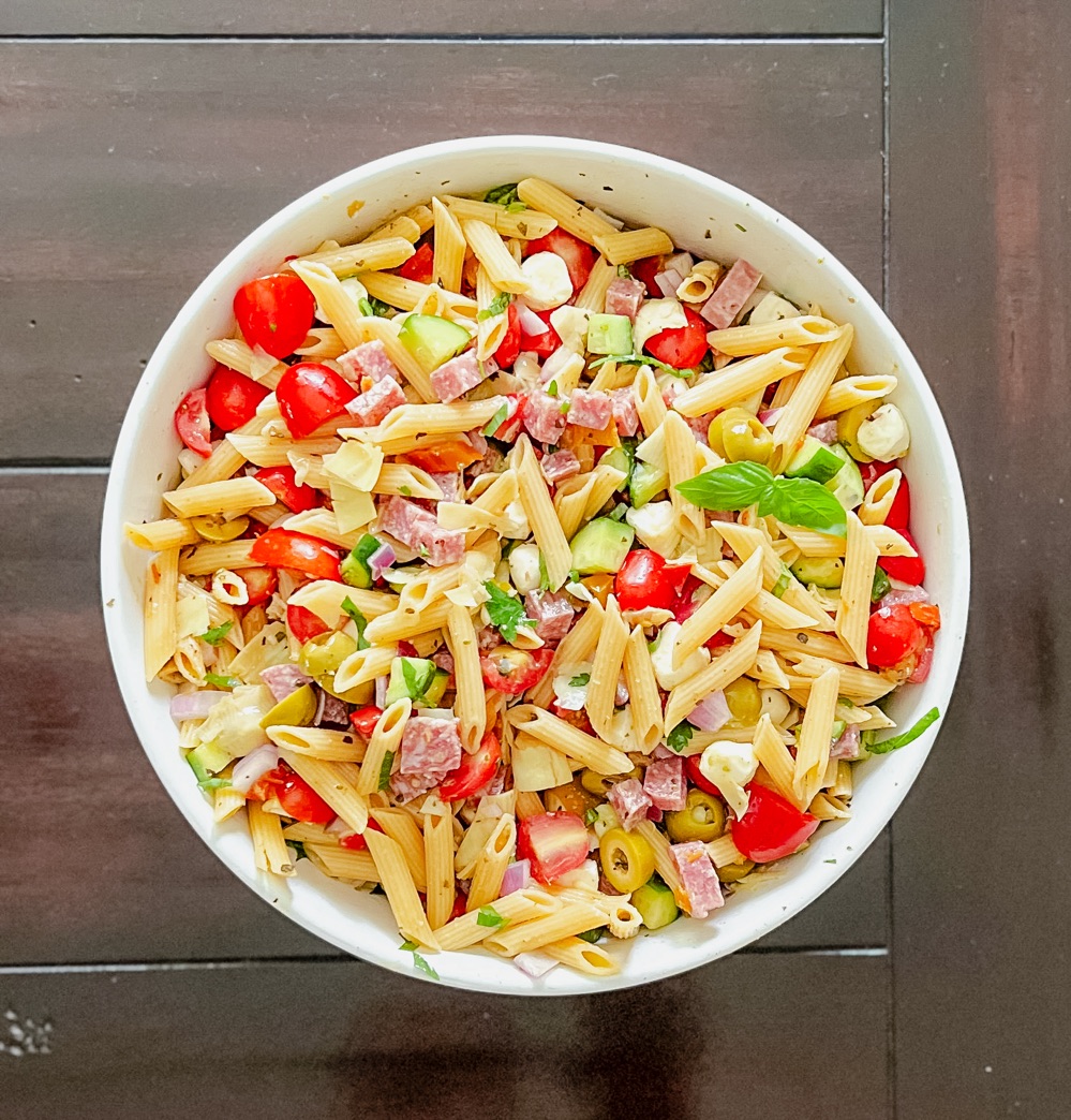 Antipasto pasta salad in a white bowl on a dark table