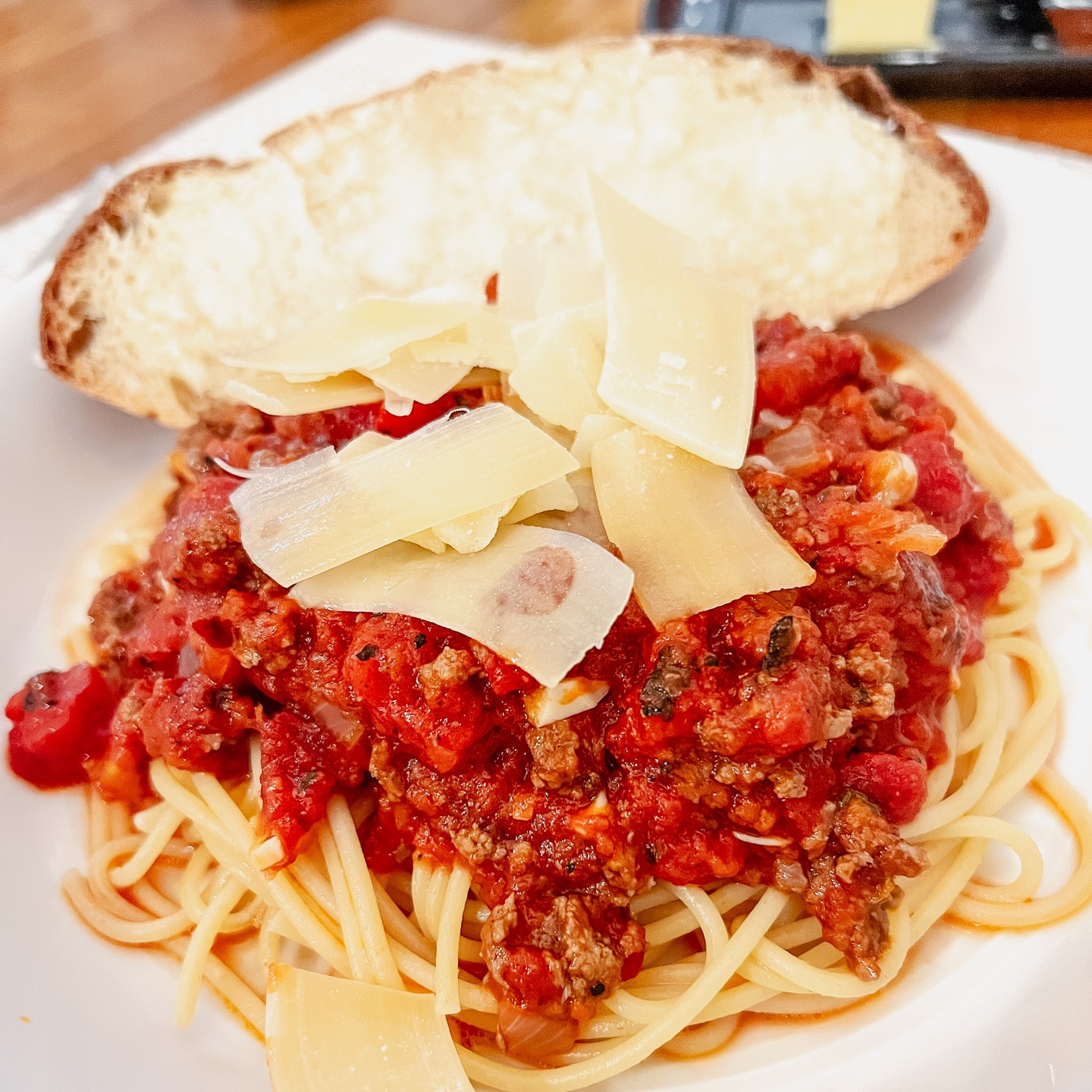 Spaghetti with tomato sauce and a slice of bread on a white plate