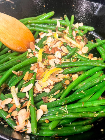 Sautéed green beans with almonds and a garlic lemon sauce in a skillet