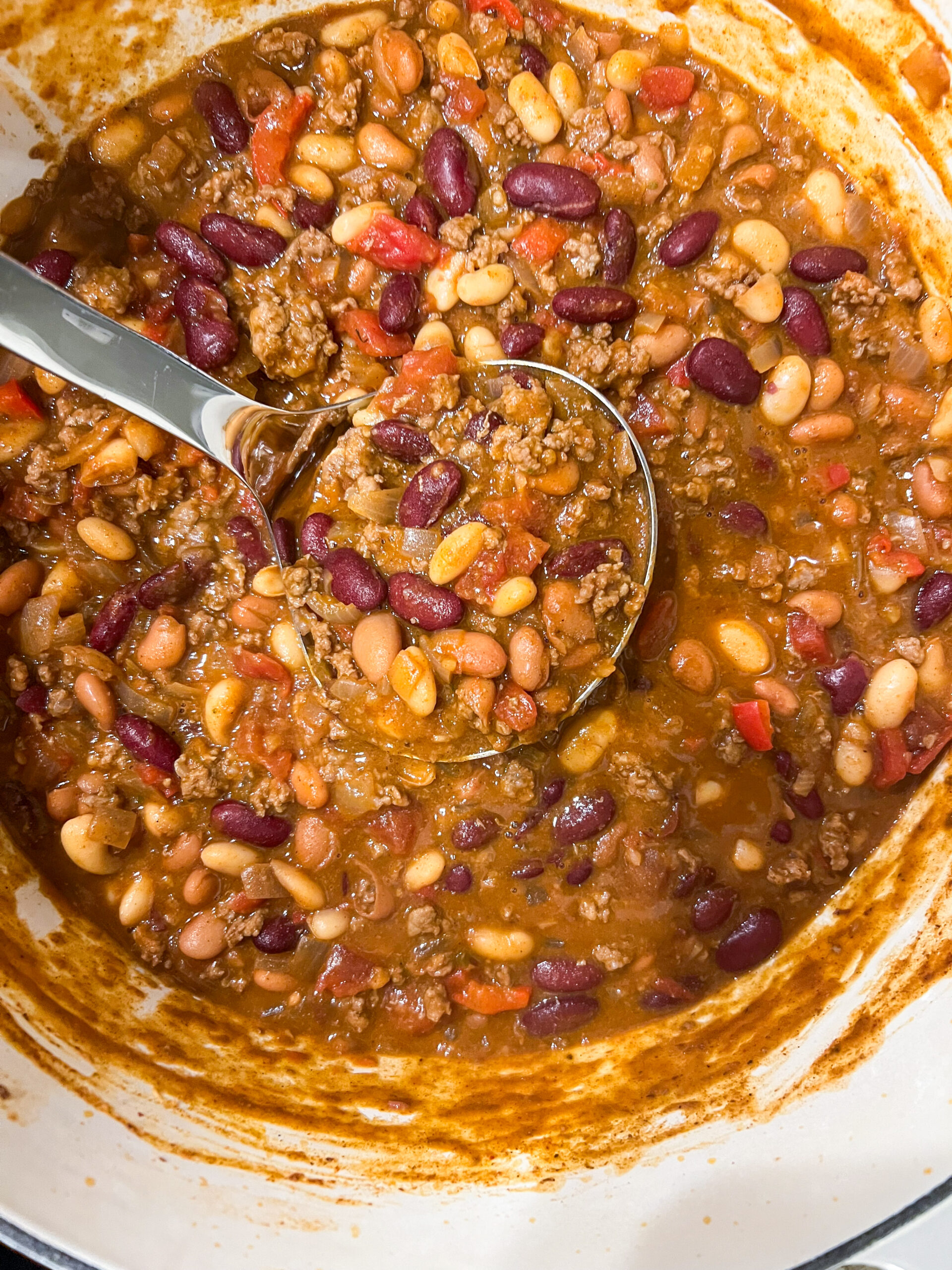 Beef chili in a Dutch oven with a ladle.