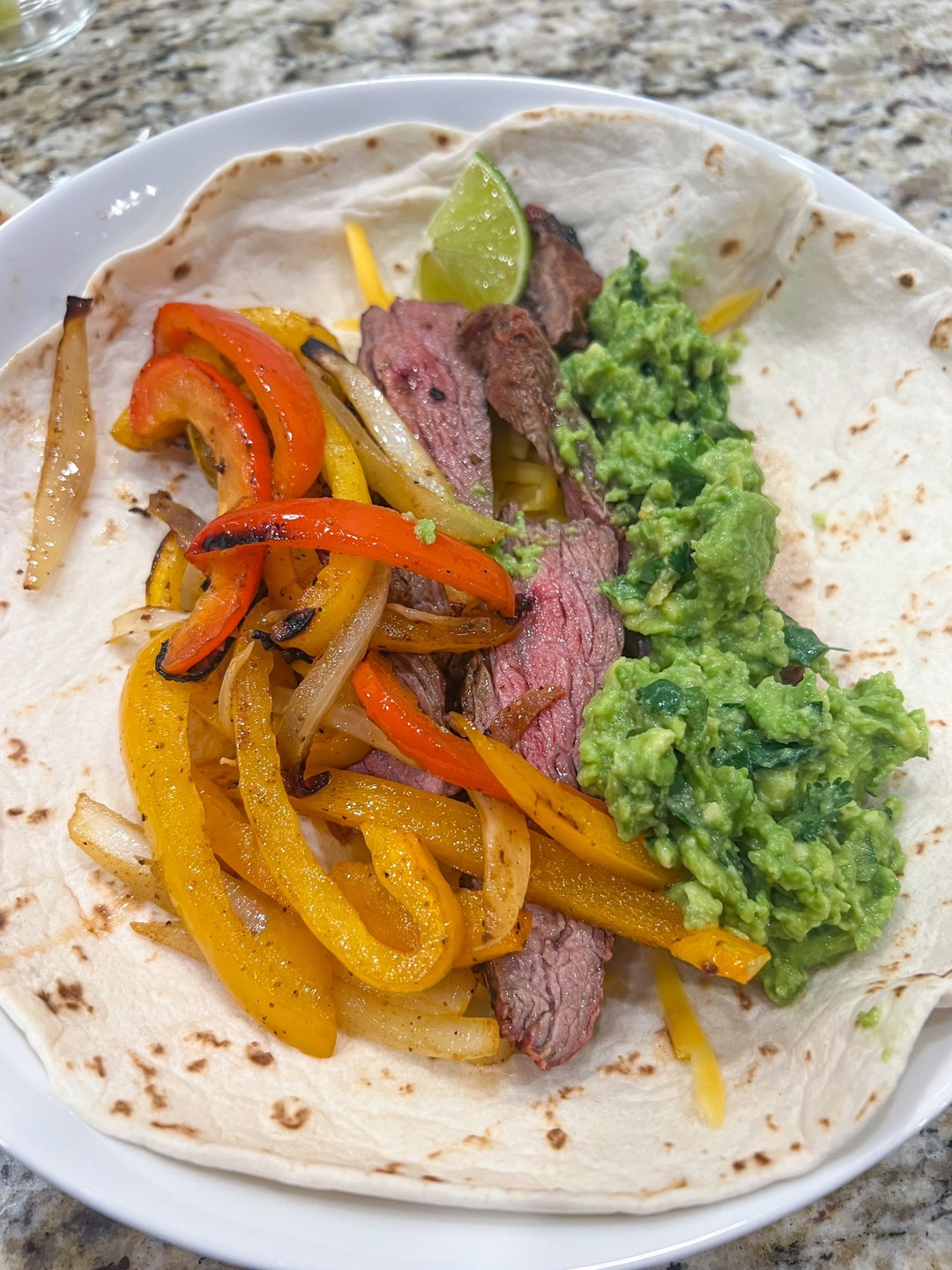 An assembled flank steak fajita on a flour tortilla with guacamole.